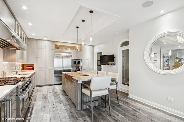 kitchen featuring high end appliances, a kitchen island, a breakfast bar, modern cabinets, and a sink