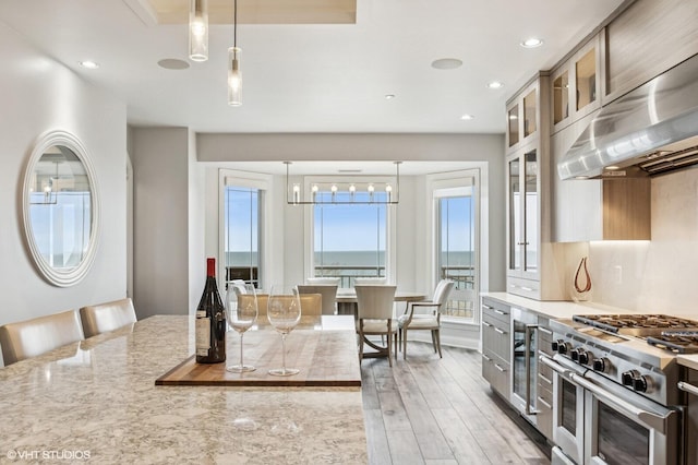 kitchen featuring exhaust hood, light wood finished floors, double oven range, and a wealth of natural light