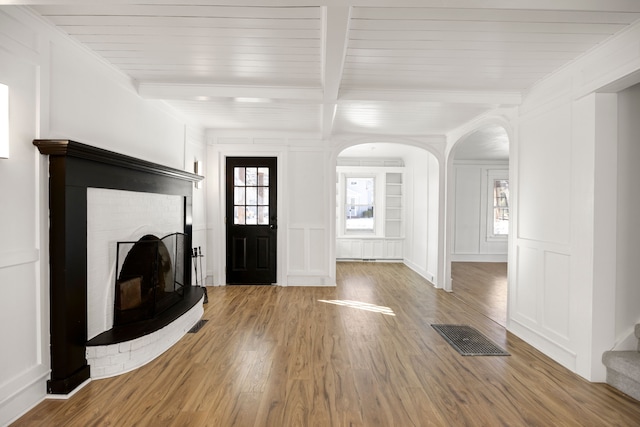 foyer with beamed ceiling, visible vents, plenty of natural light, and a decorative wall