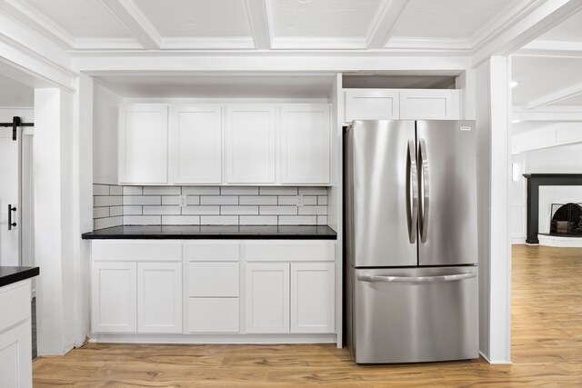 kitchen with freestanding refrigerator, dark countertops, light wood-type flooring, white cabinets, and backsplash