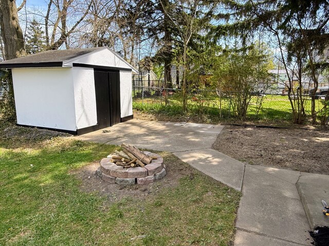 view of shed featuring fence and a fire pit