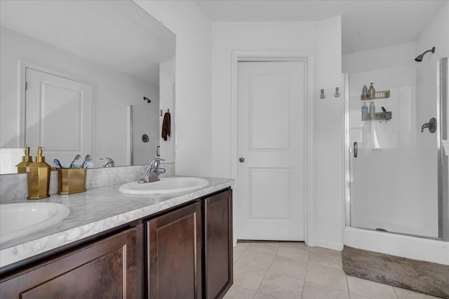 bathroom featuring a sink, double vanity, a shower stall, and tile patterned floors