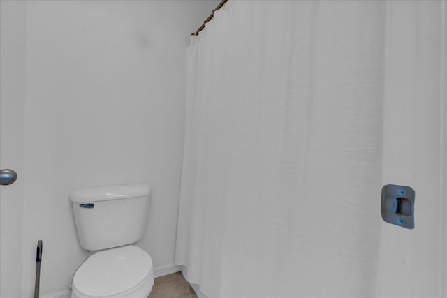 full bath featuring toilet, a shower with shower curtain, baseboards, and tile patterned floors