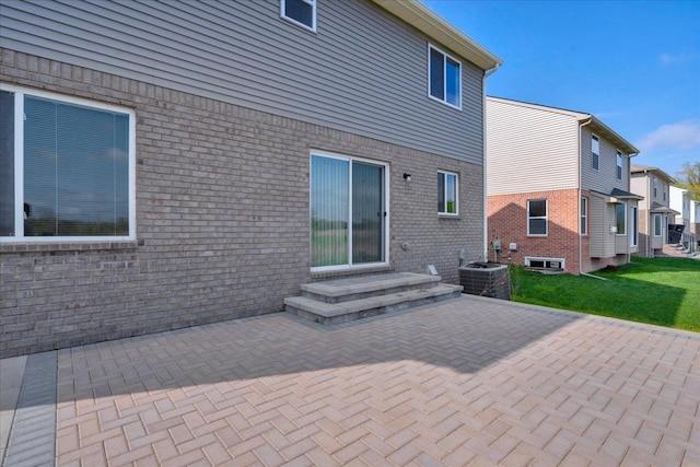 back of property with a patio area, brick siding, a residential view, central AC, and a lawn