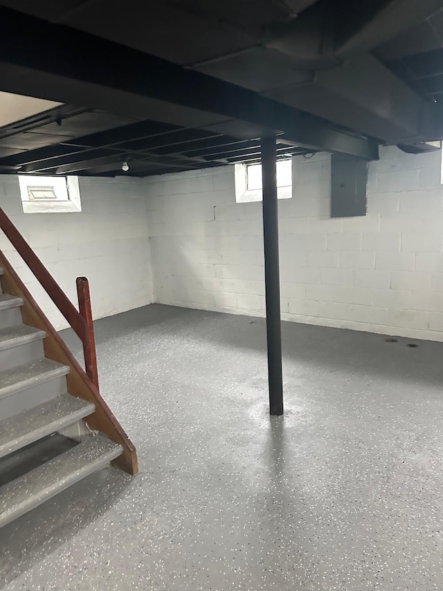 below grade area with plenty of natural light, electric panel, and stairs