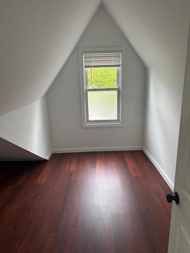 bonus room with baseboards, vaulted ceiling, and dark wood-type flooring