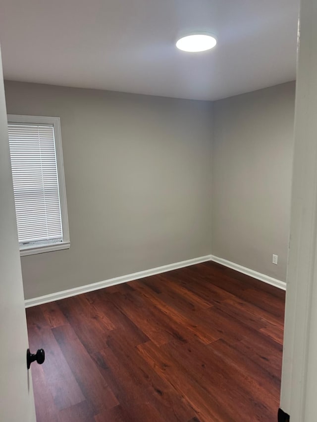 unfurnished room featuring baseboards and dark wood-type flooring