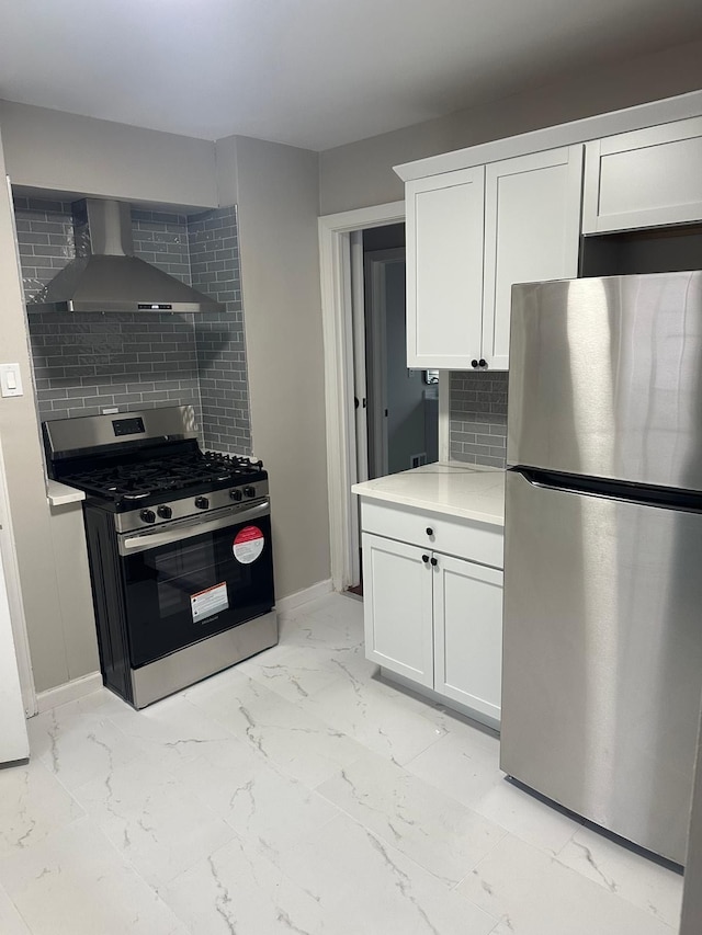 kitchen with wall chimney range hood, backsplash, white cabinets, marble finish floor, and stainless steel appliances