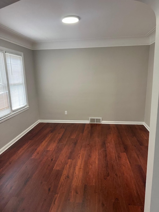 unfurnished room featuring visible vents, ornamental molding, baseboards, and dark wood-type flooring