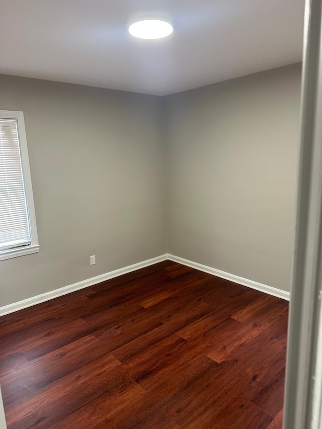 empty room featuring baseboards and dark wood-style floors