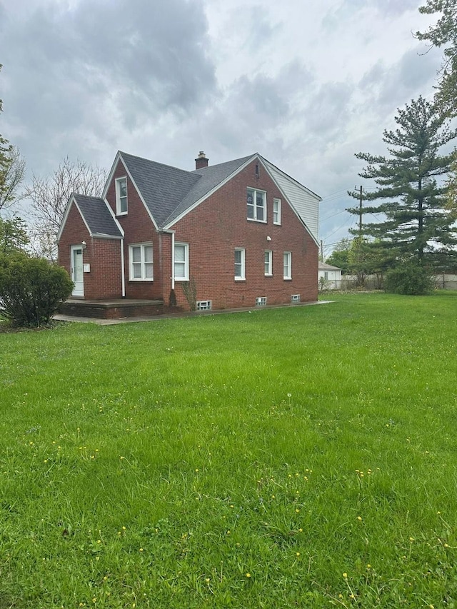 view of home's exterior featuring a lawn, brick siding, and a chimney