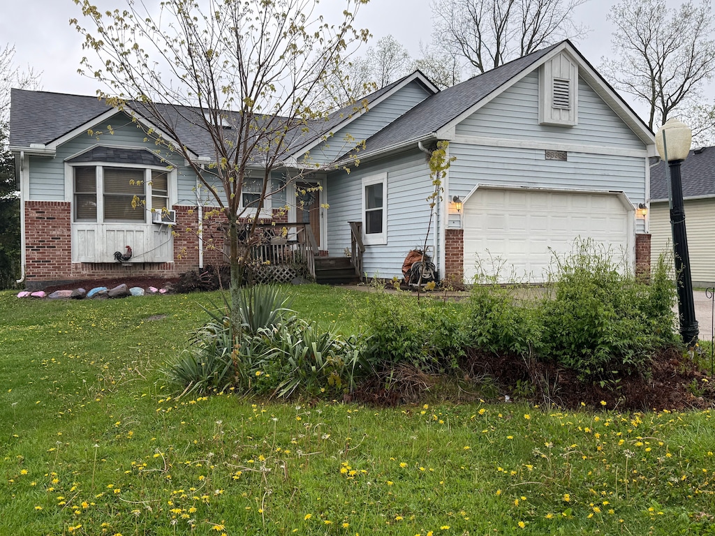 ranch-style home featuring brick siding, a front lawn, a shingled roof, and an attached garage