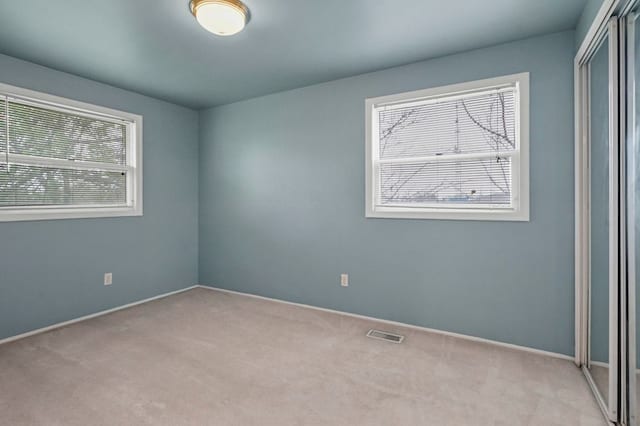 empty room featuring carpet floors, baseboards, and visible vents