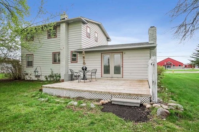 back of property with a chimney, a yard, and a deck