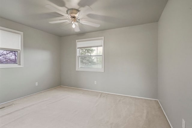 empty room with visible vents, plenty of natural light, and light carpet