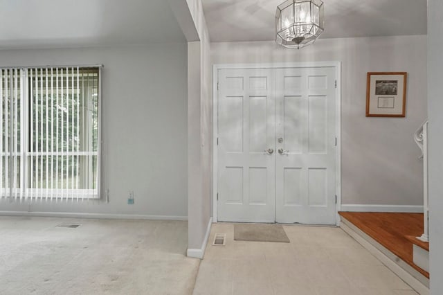 foyer featuring baseboards, tile patterned flooring, visible vents, and an inviting chandelier