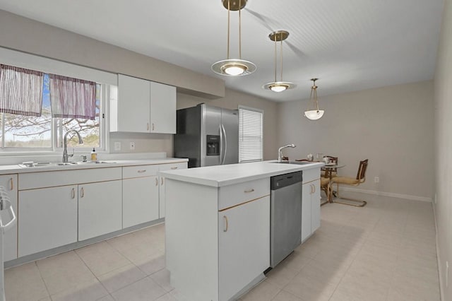 kitchen with a sink, appliances with stainless steel finishes, a center island with sink, and light countertops