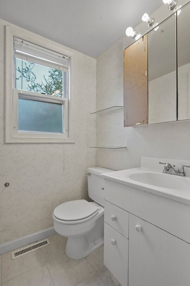 bathroom with visible vents, vanity, toilet, baseboards, and tile patterned floors