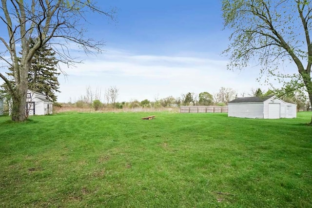 view of yard with fence, an outbuilding, and a storage unit