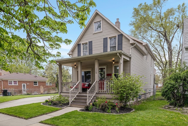 view of front of home featuring a porch, fence, a chimney, and a front lawn