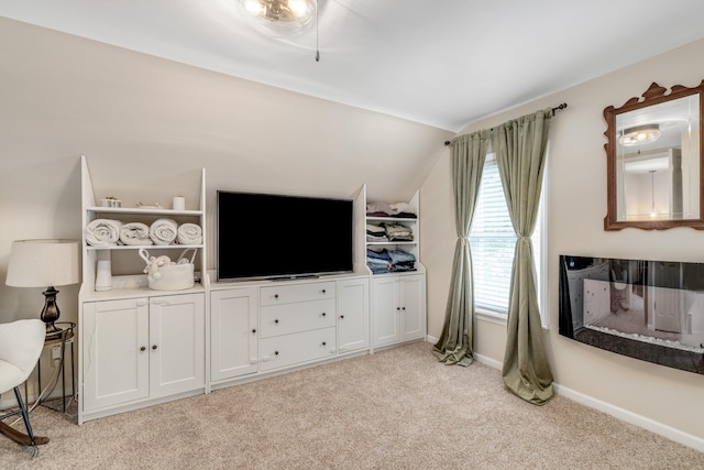 living room with baseboards, lofted ceiling, and light carpet