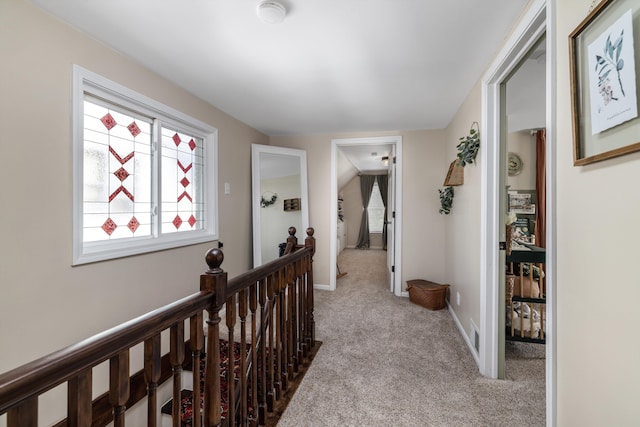 corridor featuring baseboards, carpet flooring, and an upstairs landing