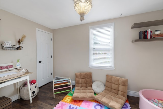 recreation room featuring baseboards, a healthy amount of sunlight, and dark wood-style floors