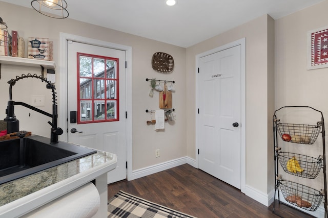 doorway featuring baseboards, a sink, dark wood finished floors, and recessed lighting