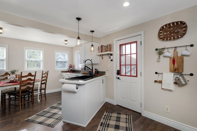 kitchen featuring a peninsula, baseboards, dark wood-style floors, and white cabinetry