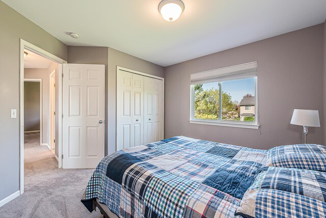 bedroom with baseboards, light colored carpet, and a closet