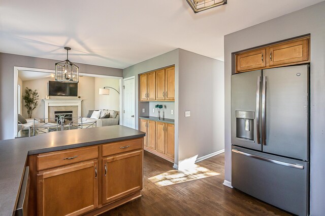kitchen featuring dark wood-style flooring, dark countertops, a fireplace, stainless steel fridge with ice dispenser, and open floor plan