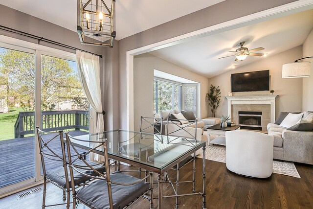 dining space with visible vents, a tile fireplace, wood finished floors, and lofted ceiling