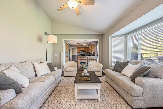 living room with a ceiling fan, vaulted ceiling, and visible vents