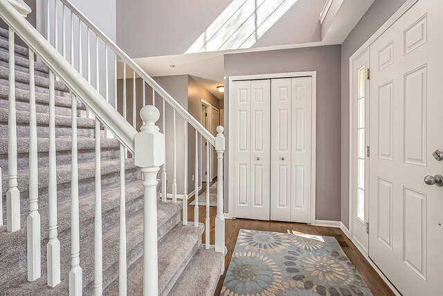 entrance foyer featuring baseboards, plenty of natural light, dark wood-style flooring, and stairs