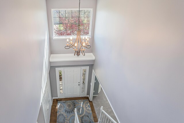 foyer entrance with baseboards, wood finished floors, and a chandelier