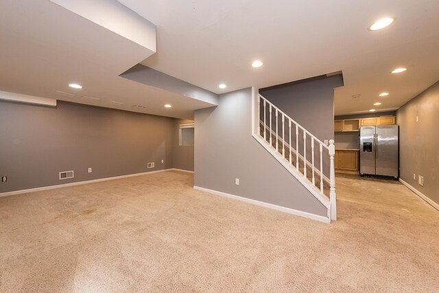 finished basement featuring light carpet, recessed lighting, baseboards, stainless steel refrigerator with ice dispenser, and visible vents