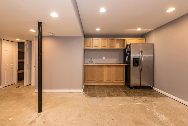 kitchen with baseboards, concrete flooring, and stainless steel refrigerator with ice dispenser