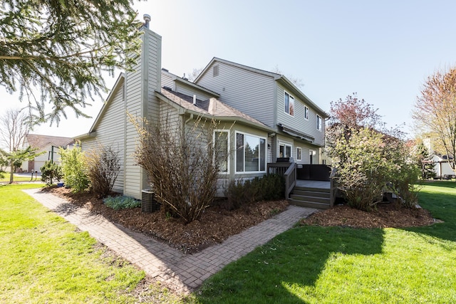 back of house featuring a yard, a deck, a chimney, and central air condition unit