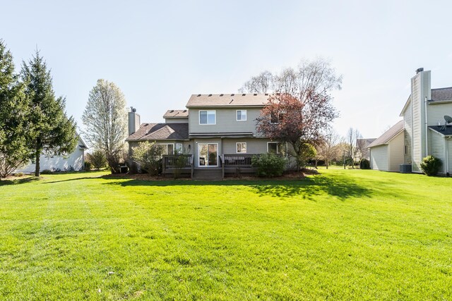 rear view of property with a lawn, cooling unit, and a deck