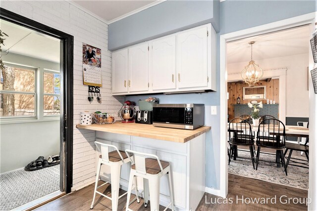 kitchen featuring white cabinets, dark wood-style flooring, stainless steel microwave, and tasteful backsplash