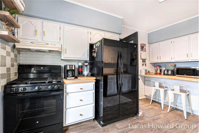kitchen featuring ornamental molding, extractor fan, white cabinets, tasteful backsplash, and black appliances