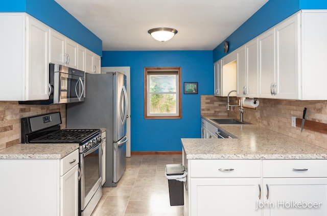 kitchen with white cabinets, appliances with stainless steel finishes, a sink, light countertops, and decorative backsplash