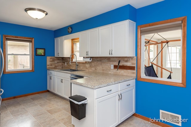 kitchen with visible vents, light countertops, a sink, backsplash, and a wealth of natural light
