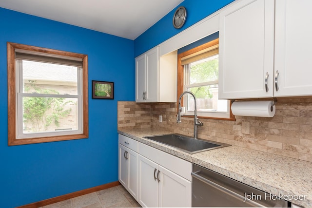 kitchen featuring stainless steel dishwasher, decorative backsplash, baseboards, white cabinetry, and a sink