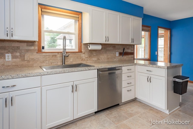 kitchen with backsplash, dishwasher, a sink, white cabinets, and a peninsula