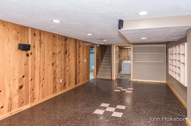 finished basement with tile patterned floors, wood walls, recessed lighting, baseboards, and washer / dryer