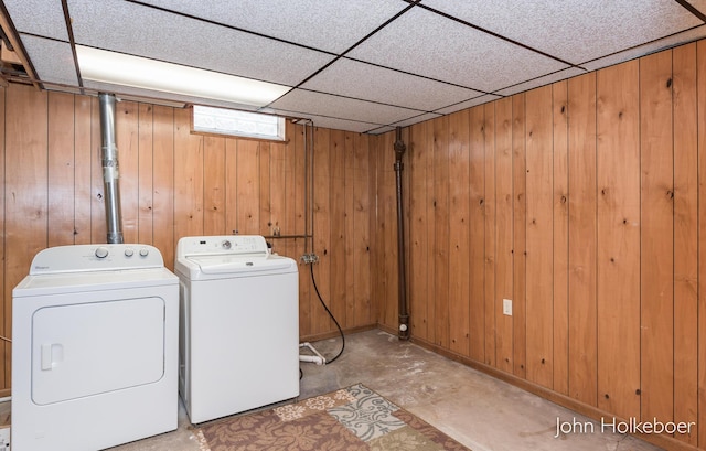 laundry area with laundry area, wood walls, and washing machine and clothes dryer