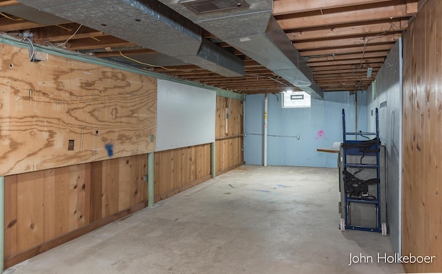 unfinished basement featuring visible vents and wood walls