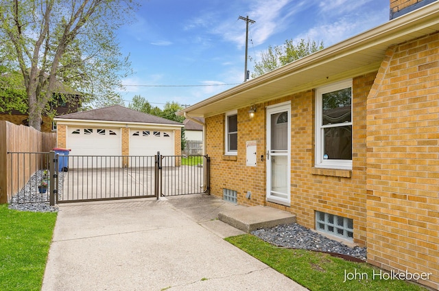 exterior space with a gate, a garage, brick siding, fence, and an outdoor structure