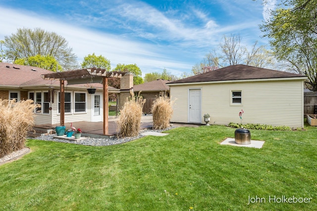 rear view of property with fence, a pergola, a deck, a lawn, and an outdoor structure